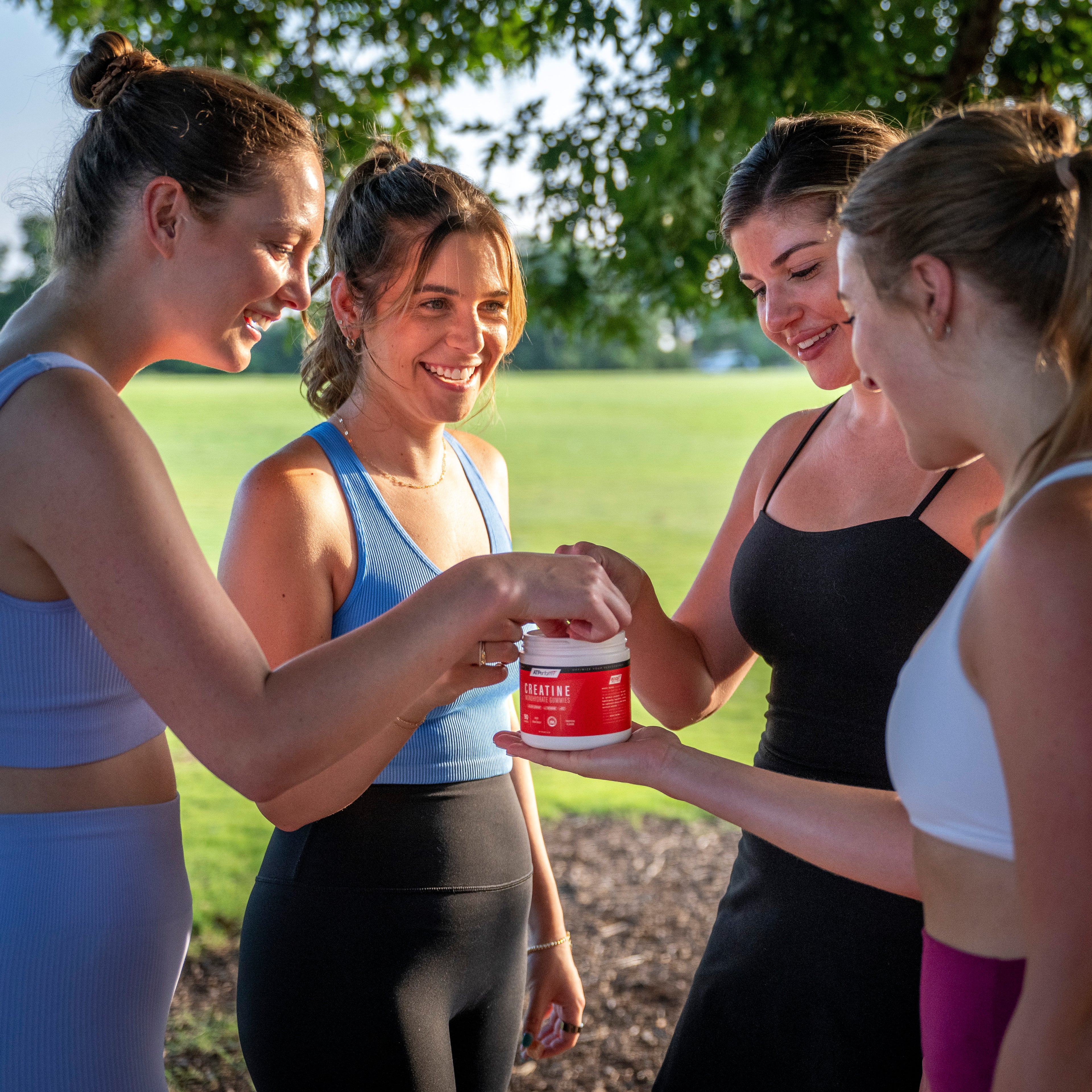 A vibrant outdoor scene featuring a diverse group of athletes engaged in running, yoga, and weightlifting, with ATPerform Creatine Monohydrate Gummies highlighted in the foreground.